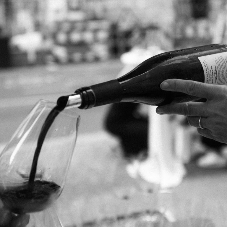 Ein Glas wird mit Rotwein aus einer Flasche gefüllt.